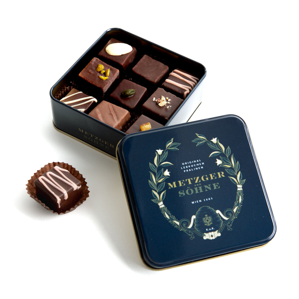 Metzger signature tin in navy blue filled with 9 different Lebkuchen 'honey cake' pralines filled with marzipan, fruits, nuts or jelly, encased in chocolate. 